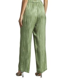 Lichtgroene wijde broek van een textuurstof met een subtiele glans. Elastische tailleband en gezoomde manchetten; gedragen met zilveren hoge hakken.