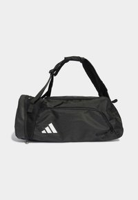 Sac de sport noir en nylon avec bandoulière ajustable, compartiment principal zippé et accent logo blanc. Dispose d'une base plate pour plus de stabilité.
