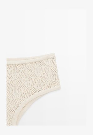 Sous-vêtements en dentelle couleur crème avec motifs tricotés géométriques et floraux, avec ceinture élastique et ouvertures pour les jambes sur fond blanc uni.