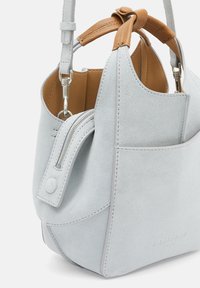 Szara torebka z zamszu z jasnobrązowym skórzanym akcentem. Posiada kieszeń na zamek, regulowany pasek na ramię oraz miękkie, teksturowane wykończenie.
