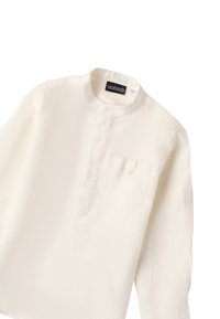 Camisa blanca de manga larga con cuello mao, bolsillo frontal y tapeta de botones. Fabricada con una tela ligera y de textura suave.