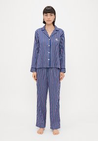 Námornícka a ružová pruhovaná pyžamová súprava obsahujúca košeľu s golierom na gombíky a nohavice s elastickým pásom, vyrobená z jemného materiálu s voľným strihom.