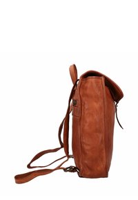 Zaino in pelle marrone con una finitura testurizzata, profilo sottile, lunghe cinghie regolabili e chiusura superiore a pattina. Dettaglio della tasca laterale visibile.