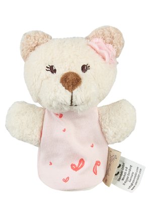 Small cream teddy bear with brown nose, embroidered eyes, pink dress with red hearts, and pink fabric flower on ear, holding a tag.