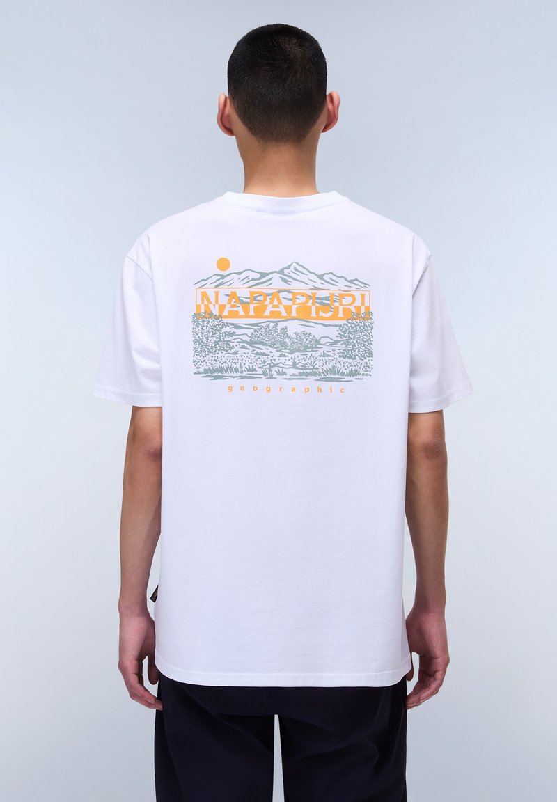 Camiseta de algodón blanca con un estampado gráfico en la parte posterior, que presenta montañas, árboles y un sol en naranja y gris. Diseño de cuello redondo simple.