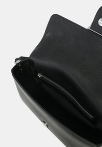 Borsa a mano in pelle nera con una texture liscia, tasca interna con zip e hardware argento, dotata di chiusura a patta e design minimalista.