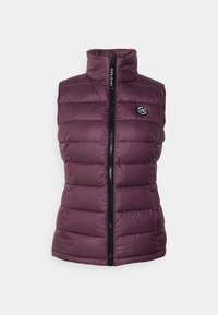 Pro šívaná vesta ve tmavě fialové barvě s vysokým límcem, předním zipem a vodorovnými prošitými sekcemi. Logo na levé straně hrudi. Hladká textura.