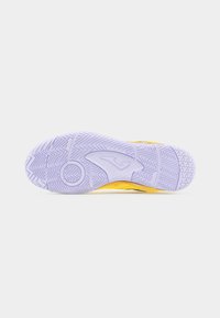 Σόλα ενός κίτρινου αθλητικού παπουτσιού με υφή από ανοιχτό μωβ καουτσούκ εξωτερικής σόλας που διαθέτει κυματοειδή και κυκλικά σχέδια πρόσφυσης.