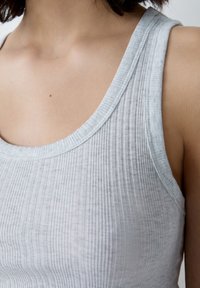 Top in cotone grigio chiaro a costine, con scollo rotondo e spalline larghe, caratterizzato da una texture morbida e un motivo sottile e uniforme.