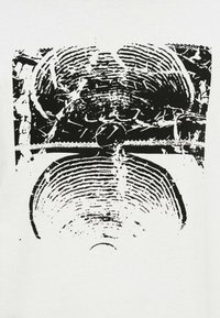 Λευκό T-shirt με έντονο μαύρο γραφικό σχέδιο από συμπαγείς κυκλικές γραμμές, που μοιάζουν με δακτυλίους δέντρων ή ηχητικά κύματα, με υφή.