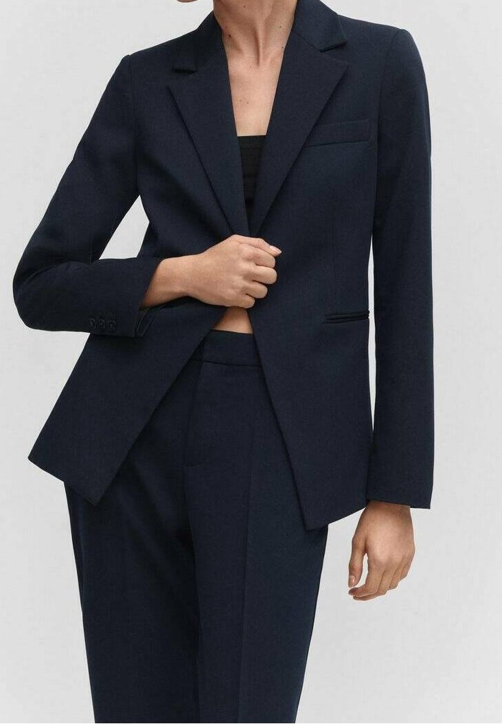Blazer bleu marine foncé avec une coupe ajustée, fermeture à un bouton et revers crantés. Comprend une poche poitrine et des épaules structurées.