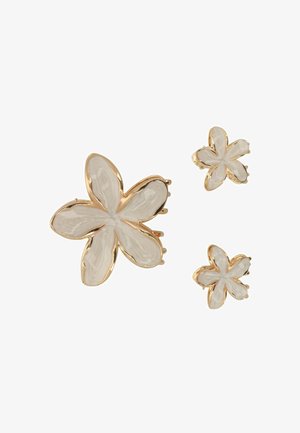 Orecchini floreali color oro con finitura smaltata bianca testurizzata; include un grande orecchino a clip a forma di fiore e due orecchini a perno più piccoli.