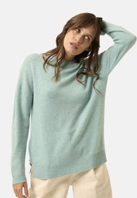 Helles Teal langärmliges Sweatshirt mit lockerer Passform, geripptem Kragen und Saum. Weiche Textur, seitliche Schlitze am unteren Rand und minimalistisches Design.