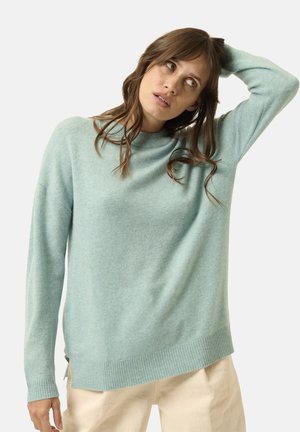 Helles Teal langärmliges Sweatshirt mit lockerer Passform, geripptem Kragen und Saum. Weiche Textur, seitliche Schlitze am unteren Rand und minimalistisches Design.