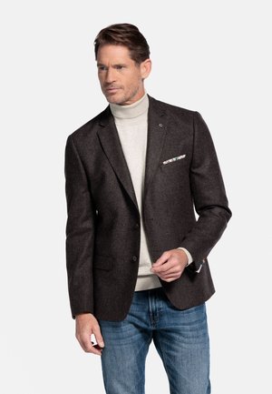 Brauner Wollblazer mit Reverskragen, Ein-Knopf-Verschluss und zwei Vorderseiten-Taschen. Getragen über einem hellgrauen Rollkragenpullover und blauen Jeans.