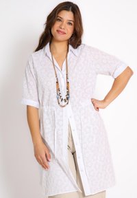 Witte kanten blouse met korte mouwen, knoopsluiting aan de voorkant, decoratieve bloemen uitsparingen, kraag en een relaxte pasvorm. Inclusief een met kralen versierde ketting.
