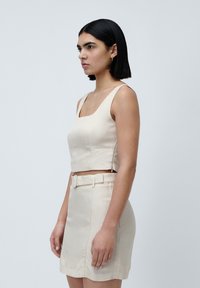 Beige linned crop top og mini nederdel sæt, der har en firkantet udskæring, smalle stropper og et bælte i højtalje design.