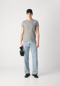 Γκρι κοντομάνικο t-shirt, ανοιχτό μπλε τζιν παντελόνι, μαύρο καπέλο και μαύρα παπούτσια. Κρατάει μια μαύρη τσάντα, μίνιμαλ σχέδιο, casual εφαρμογή.