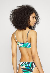 Conjunto de biquíni com um padrão de folhas tropicais multicoloridas em azul, verde e laranja. O top tem alças finas e um fecho nas costas.