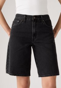 Zwarte denim bermuda shorts met een hoge taille, voorzien van vijf zakken, koperen hardware en een rafelige zoom. Gestructureerde, stevige stof.
