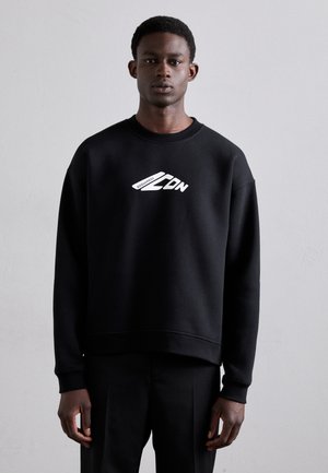 Sweatshirt noir avec un col rond et des poignets côtelés, arborant un texte graphique blanc. Texture lisse, coupe ample et design minimaliste.