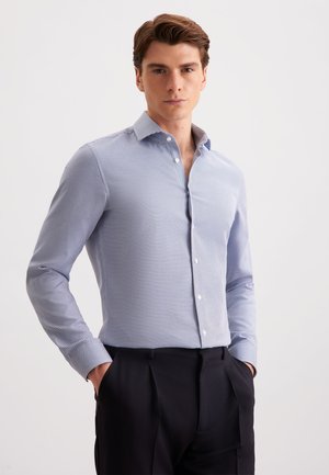 Hellblau kariertes Hemd mit Button-Down-Kragen, langen Ärmeln und weißen Knöpfen, getragen mit navyblauen Hosen. Glatte Textur.