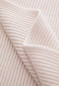 Light pink ribbed fabric folded, showing thick texture and soft, knitted pattern. The edges are slightly curled, revealing the fabric's depth.
