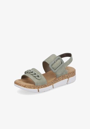Green suede sandals with a braided strap, a large buckle, and a textured cork sole, featuring a white platform base.