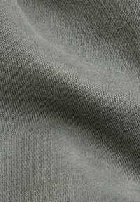 Tejido de punto gris que muestra una textura suave con un tejido fino. El material parece blando y flexible, adecuado para prendas.