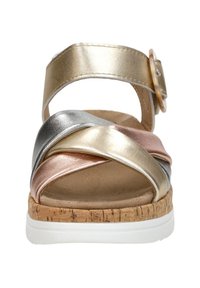 Metallische Sandalen mit Riemchen, die verwobene goldene, silberne und roségoldene Bänder aufweisen. Korkstrukturierter Keilabsatz mit einer weißen Gummisohle.