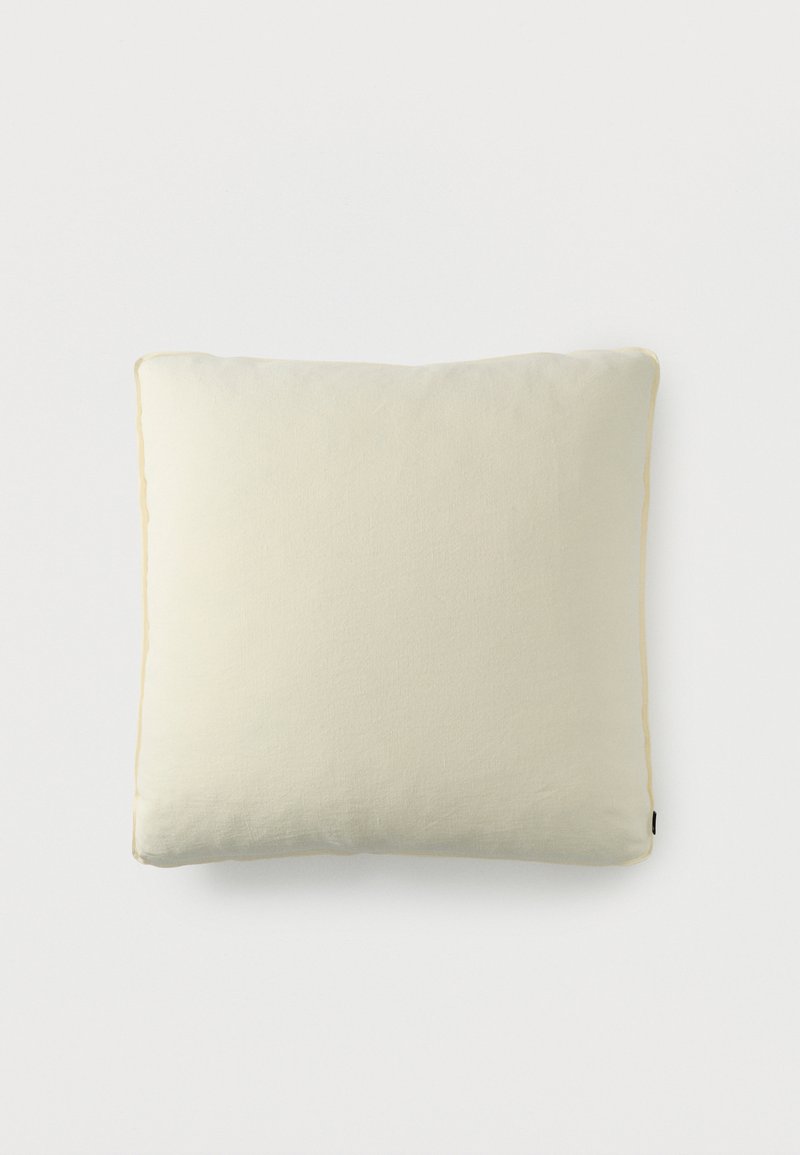 Τετράγωνο διακοσμητικό μαξιλάρι σε κρεμ απόχρωση με μαλακό υφασμάτινο κάλυμμα, σε απλό λευκό φόντο.
