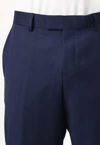 Pantalones de color azul marino con patrón, confeccionados en tejido texturizado, con una parte frontal plana y bolsillos laterales, que ofrecen un corte ajustado y lazo para cinturón.