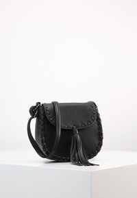 Czarna skórzana torebka typu crossbody z plecionym akcentem, o zaokrąglonym kształcie, z zapięciem na klapkę i ozdobnym chwostem. Gładka faktura i regulowany pasek.