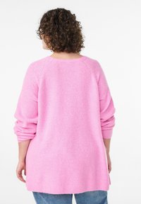 Nadrozmerný sveter s dlhými rukávmi v jemnej ružovej pletenine. Charakterizuje ho rebrovaná textúra, okrúhly výstrih a bočné rozparky pre pohodlný pohyb.