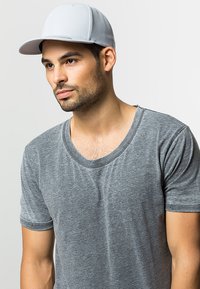 Grå bomulds t-shirt med bred halsudskæring; parret med en lys grå kasket med et struktureret, tekstureret design.
