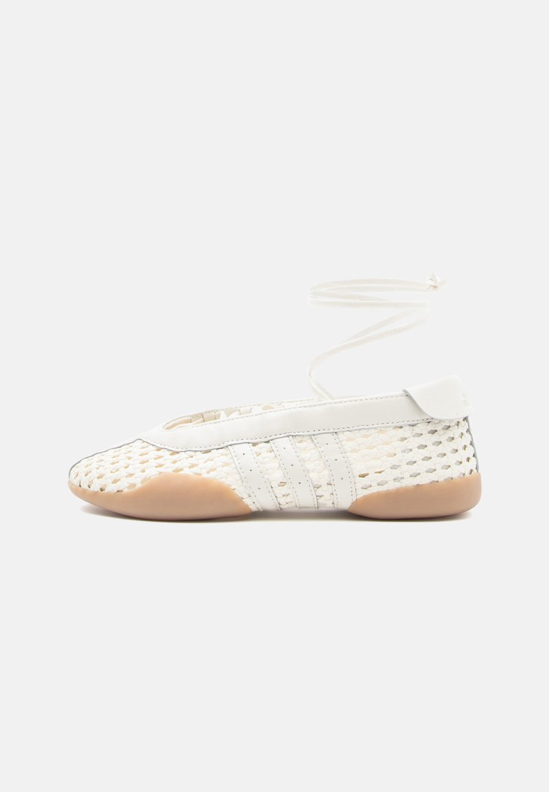 Weißer gewebter Schuh mit strukturierter Oberseite, rundem Zehenbereich, weißen Lederakzenten und flexiblem Gummisohlen. Dünne Schnürsenkel befestigt.