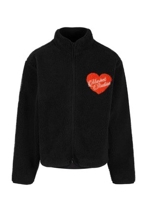 Zwarte fleecjacket met een ritssluiting, voorzien van een rood hartontwerp en "Market Studios" geborduurd in het wit. Zachte textuur overal.