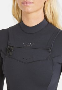 Schwarzer Neoprenanzug mit glattem, dehnbarem Material. Verfügt über einen Reißverschluss am Hals, nahtlose Nähte und dezente Markenkennzeichnung auf der Brust.