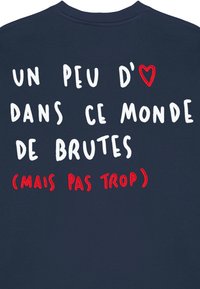 Námornícky modrý sveter s bielym a červeným vyšívaným textom. Dizajn obsahuje symbol srdca, ktorý vyjadruje hravú správu vo francúzštine.