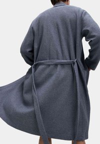 Roba grigia scura, strutturata, con design avvolgente, maniche lunghe e una cintura in vita, caratterizzata da una forma fluida e un tessuto morbido.