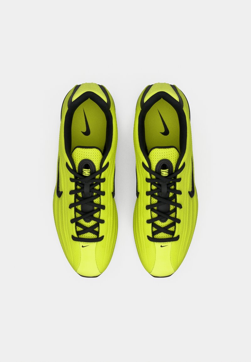 Klart gula-gröna Nike löparskor med svarta snören och swoosh-loggor, sett uppifrån på en vit bakgrund.