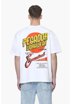 White cotton t-shirt featuring bold yellow and red graphic text on the back. Design includes circular elements and textual details.