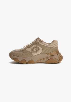 Beige en bruine chunky sneaker met mesh en leren panelen, ronde neus, vetersluiting aan de voorkant en een geprofileerde zool, met een cirkelvormig logo aan de zijkant.