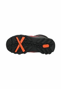 Suela de zapato de goma negra con surcos profundos, un acento naranja con "zona de flexión" y un diseño texturizado para mejorar el agarre.