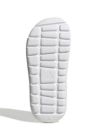Bela podplat športnih copat z teksturiranimi, izbočenimi vzorci in krožnimi poudarki. V središču se nahaja majhna, vtisnjena adidas logotip.