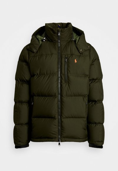 Σκοτεινό πράσινο μπουφάν με ψηλό γιακά, κουκούλα και φερμουάρ μπροστά. Διαθέτει οριζόντια επένδυση, τσέπη με φερμουάρ στο στήθος και λεπτομέρεια λογότυπου.