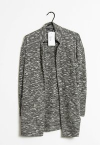 Cardigan grigio a trama con design aperto, dotato di un ampio colletto e due tasche laterali, appeso a un gancio nero.