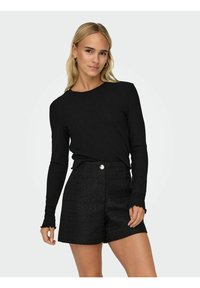 Svart ribbad långärmad topp med rund halsringning, i kombination med högmidjade texturerade svarta shorts med en framknappdetalj.