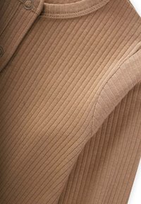 La camiseta de manga larga marrón con costillas presenta un escote redondo con acentos de botones. La tela tiene una textura suave y sutiles rayas verticales.
