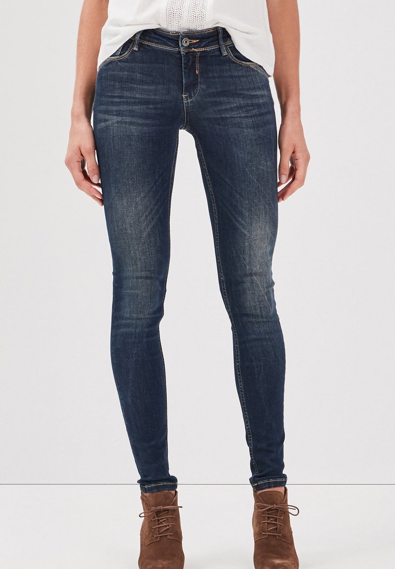 Mörkblå skinny jeans med en blekt tvätt, framfickor och midjehög passform, kombinerat med bruna mocka ankelboots.